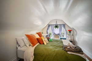 Bedroom with lofted ceiling and wood-type flooring