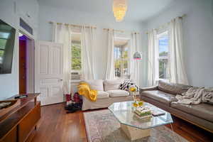 Living room with a wealth of natural light, dark wood-type flooring, and a chandelier