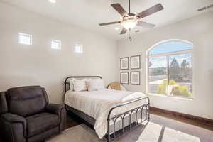 Carpeted bedroom featuring multiple windows and ceiling fan