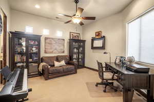 Home office with ceiling fan and light colored carpet