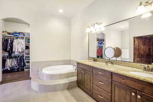 Bathroom featuring tiled bath, vanity, and wood-type flooring