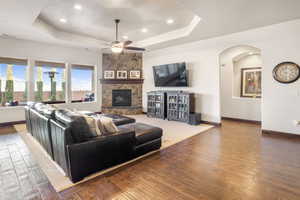 Living room with a fireplace, hardwood / wood-style floors, a tray ceiling, and ceiling fan