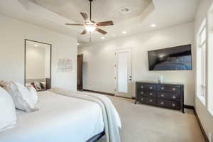 Carpeted bedroom with ceiling fan and a raised ceiling