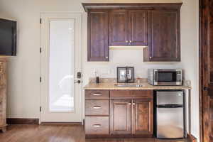 Kitchen featuring light stone counters, sink, appliances with stainless steel finishes, and dark hardwood / wood-style flooring