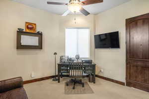 Carpeted office featuring ceiling fan