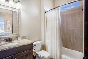 Full bathroom featuring shower / bath combo with shower curtain, toilet, plenty of natural light, and vanity