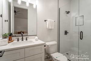 Bathroom featuring vanity, toilet, an enclosed shower, and ceiling fan