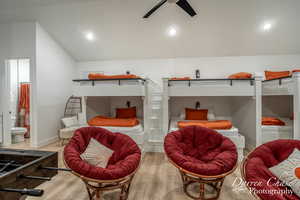 Bedroom with vaulted ceiling, hardwood / wood-style floors, ceiling fan, and connected bathroom