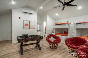 Interior space featuring a wall mounted AC, a textured ceiling, ceiling fan, lofted ceiling, and light hardwood / wood-style floors