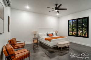 Bedroom with ceiling fan, an AC wall unit, and a textured ceiling