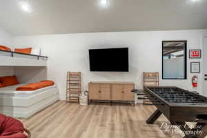 Game room with a textured ceiling and light hardwood / wood-style flooring