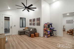 Living room featuring high vaulted ceiling, ceiling fan, and light wood-type flooring