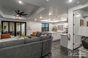 Living room featuring a wall mounted AC, a tray ceiling, a textured ceiling, and ceiling fan