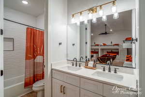 Full bathroom with lofted ceiling, toilet, shower / bath combo with shower curtain, and vanity