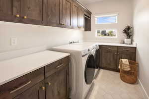 Laundry area featuring light tile patterned floors, cabinets, and washer and clothes dryer