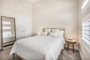 Bedroom with dark carpet, a closet, and a high ceiling