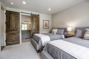 Carpeted bedroom featuring a textured ceiling and a barn door