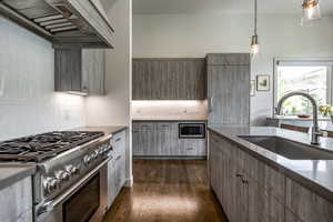 Kitchen featuring sink, hanging light fixtures, dark hardwood / wood-style flooring, high end stainless steel range, and custom exhaust hood