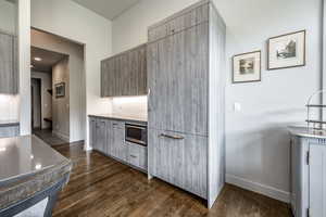 Kitchen with stainless steel microwave and dark wood-type flooring