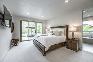 Bedroom featuring light colored carpet, a textured ceiling, and access to outside