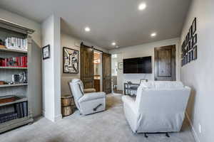 Living room featuring a barn door and light carpet