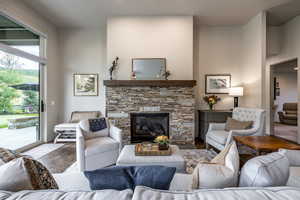 Living room with a stone fireplace and wood-type flooring