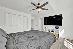 Bedroom with ceiling fan, a closet, and light hardwood / wood-style floors