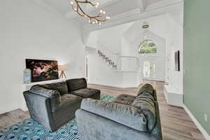 Living room featuring light wood-type flooring, high vaulted ceiling, an inviting chandelier, and beam ceiling