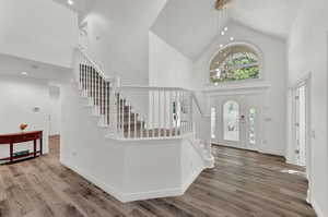 Entrance foyer featuring hardwood / wood-style floors, high vaulted ceiling, and a notable chandelier