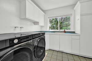 Laundry area with washer and clothes dryer, cabinets, and sink