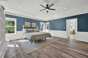 Bedroom featuring ceiling fan, hardwood / wood-style flooring, multiple windows, and connected bathroom