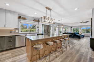 Kitchen featuring hanging light fixtures, ceiling fan with notable chandelier, appliances with stainless steel finishes, a kitchen breakfast bar, and a kitchen island