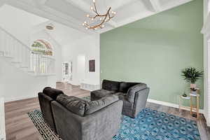 Living room with high vaulted ceiling, wood-type flooring, an inviting chandelier, and beamed ceiling