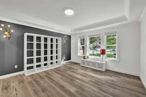 Empty room featuring hardwood / wood-style floors, a chandelier, and ornamental molding