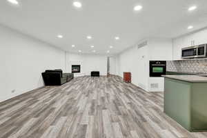 Kitchen featuring a fireplace, oven, white cabinetry, and light hardwood / wood-style flooring