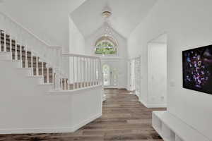 Entryway featuring high vaulted ceiling, hardwood / wood-style floors, and a notable chandelier