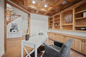 Office with coffered ceiling, light hardwood / wood-style floors, and beam ceiling