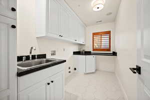 Interior space featuring hookup for a washing machine, cabinets, light tile patterned floors, sink, and hookup for a gas dryer