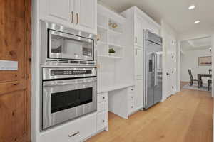 Kitchen featuring light hardwood / wood-style flooring, built in appliances, and white cabinets