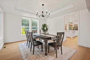 Dining space featuring light wood-type flooring, a raised ceiling