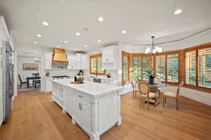 Kitchen with plenty of natural light, custom range hood, white cabinets, and a kitchen island