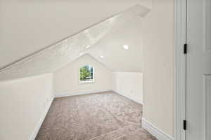 Additional living space featuring carpet floors, a textured ceiling, and vaulted ceiling