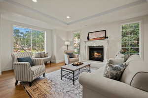 Living room featuring hardwood / wood-style flooring, plenty of natural light, a high end fireplace, and ornamental molding