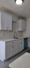 Kitchen featuring dishwasher, sink, white cabinets, and tile patterned floors