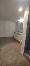 Bonus room with sink, light carpet, and a textured ceiling