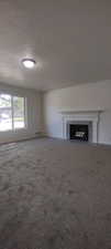 Unfurnished living room with carpet flooring and a textured ceiling