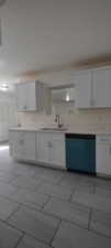 Kitchen with stainless steel dishwasher, sink, light tile patterned floors, and white cabinets