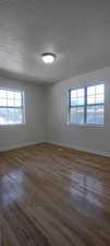 Empty room featuring dark hardwood / wood-style floors and a textured ceiling