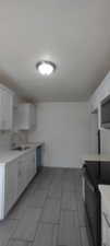 Kitchen featuring light tile patterned floors, white cabinetry, black range, and sink