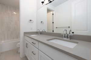 Full bathroom featuring tiled shower / bath combo, vanity, toilet, and tile patterned floors